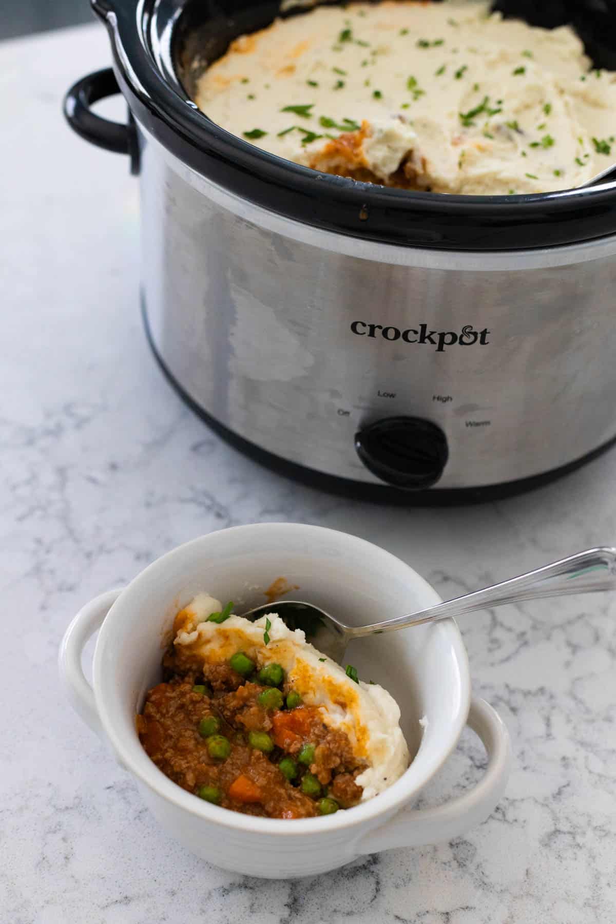 A bowl of the shepherds pie is served up and sits in front of the Crockpot where it cooked.