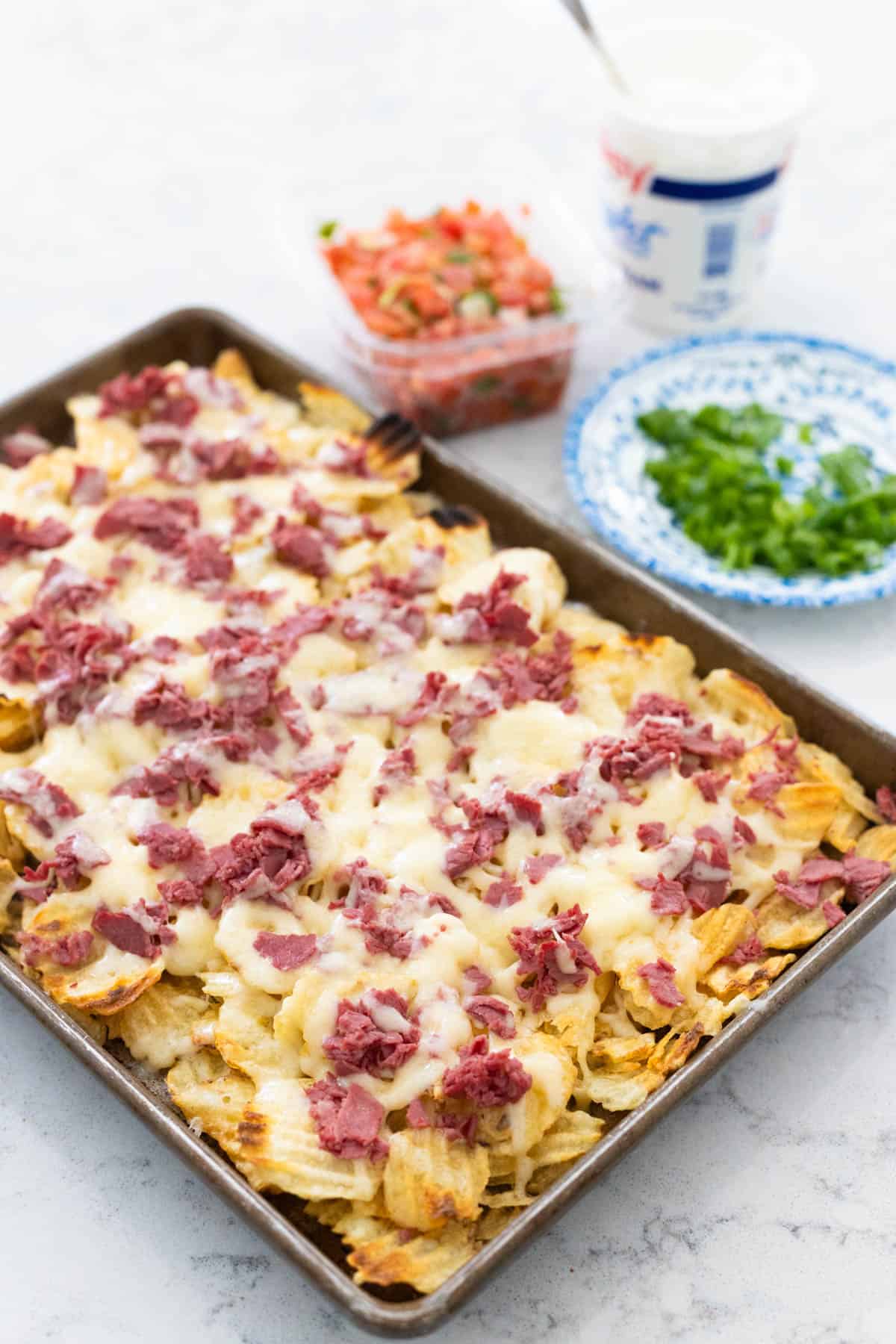 The pan of nachos is on the counter fresh from the oven.