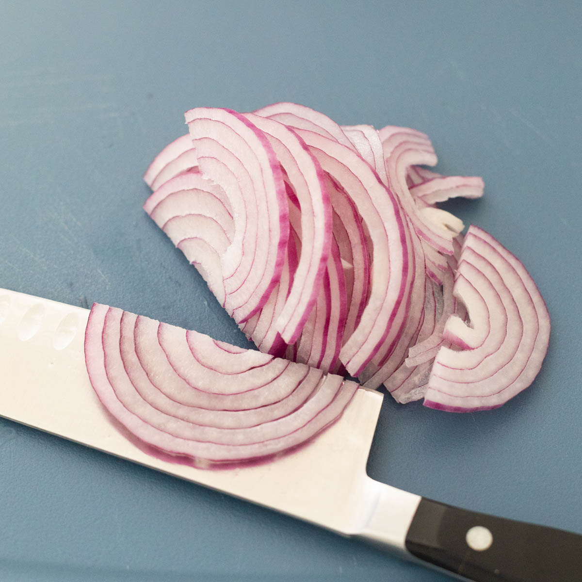 The red onion has been cut in half and then sliced very thinly.
