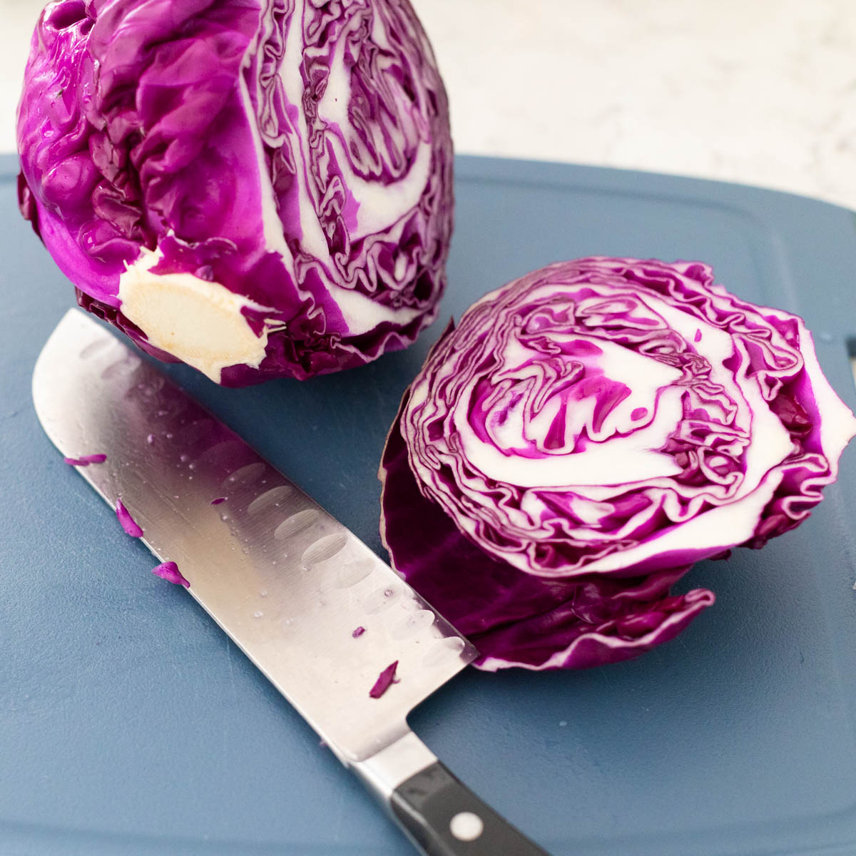 The knife has cut the cabbage head just off from center of the stem.