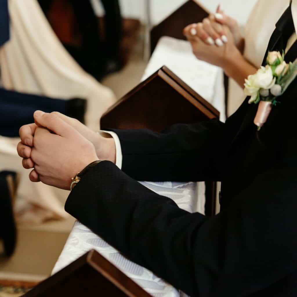 A teen boy and a teen girl knee in church during their confirmation mass.