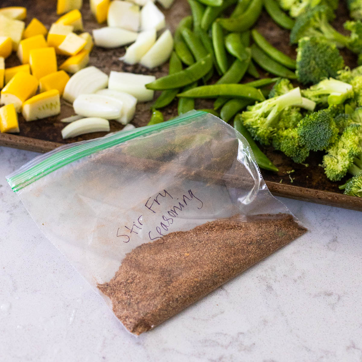 A bag of seasoning is on the counter next to a pan of vegetables.
