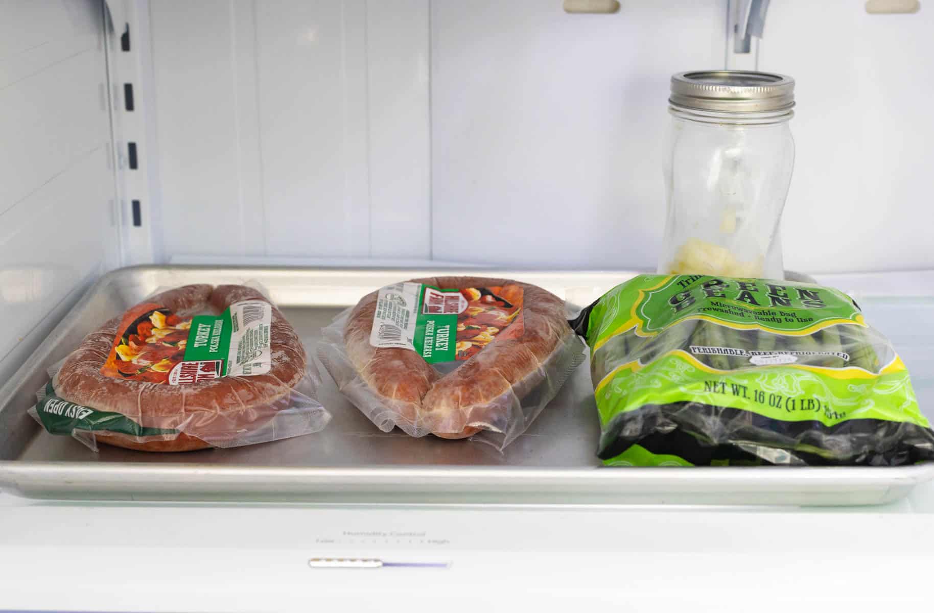 A baking sheet inside the fridge has the meat and veggies for making dinner tonight.
