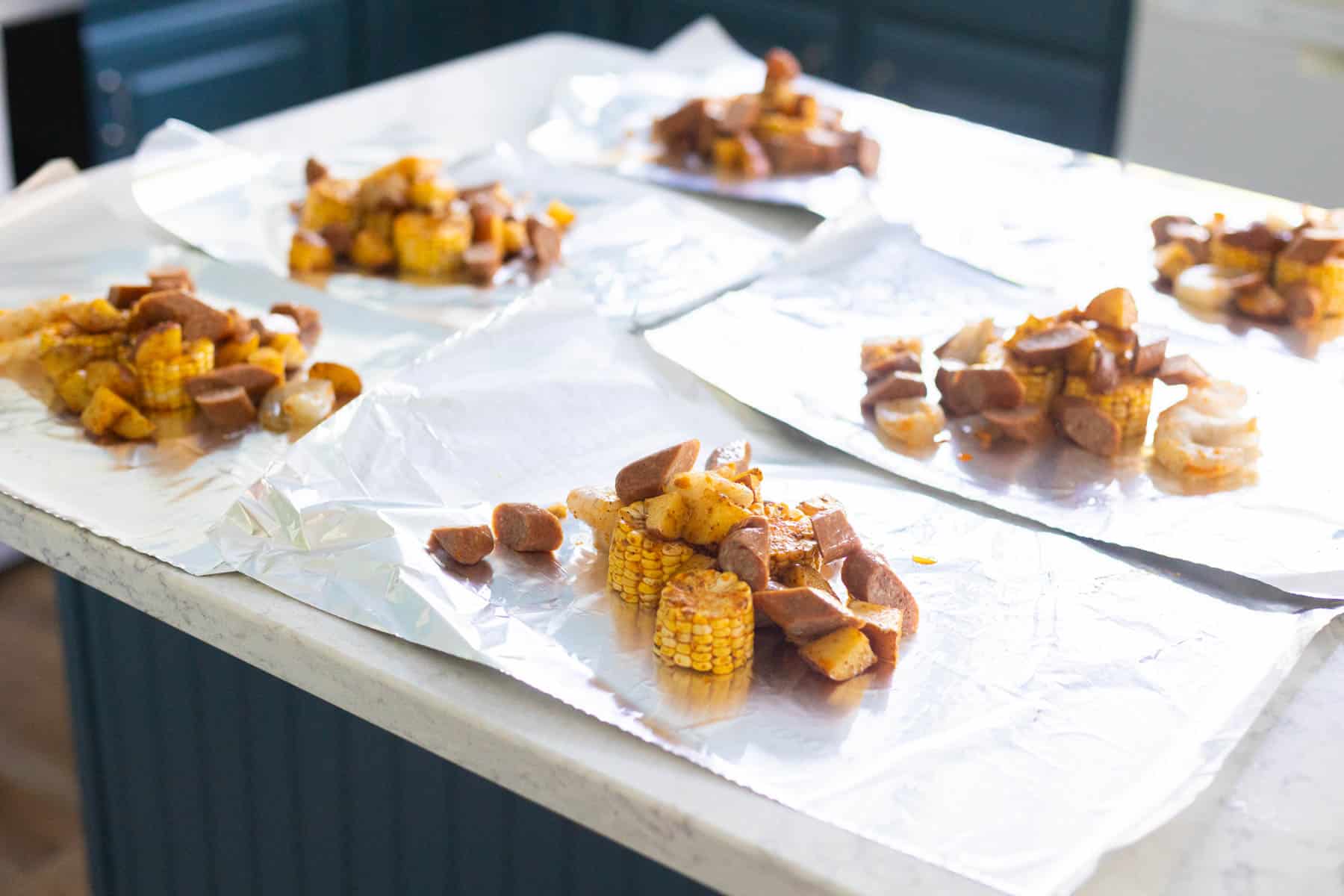 The portions of aluminum foil have been topped with the shrimp mixture.