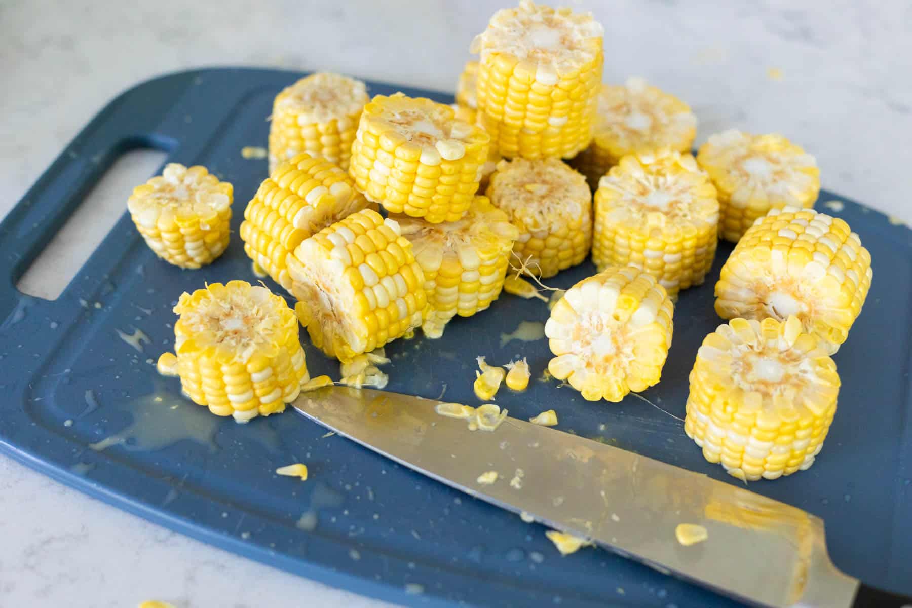 The corn cobs have been cut into 1-inch wheels on a cutting board.