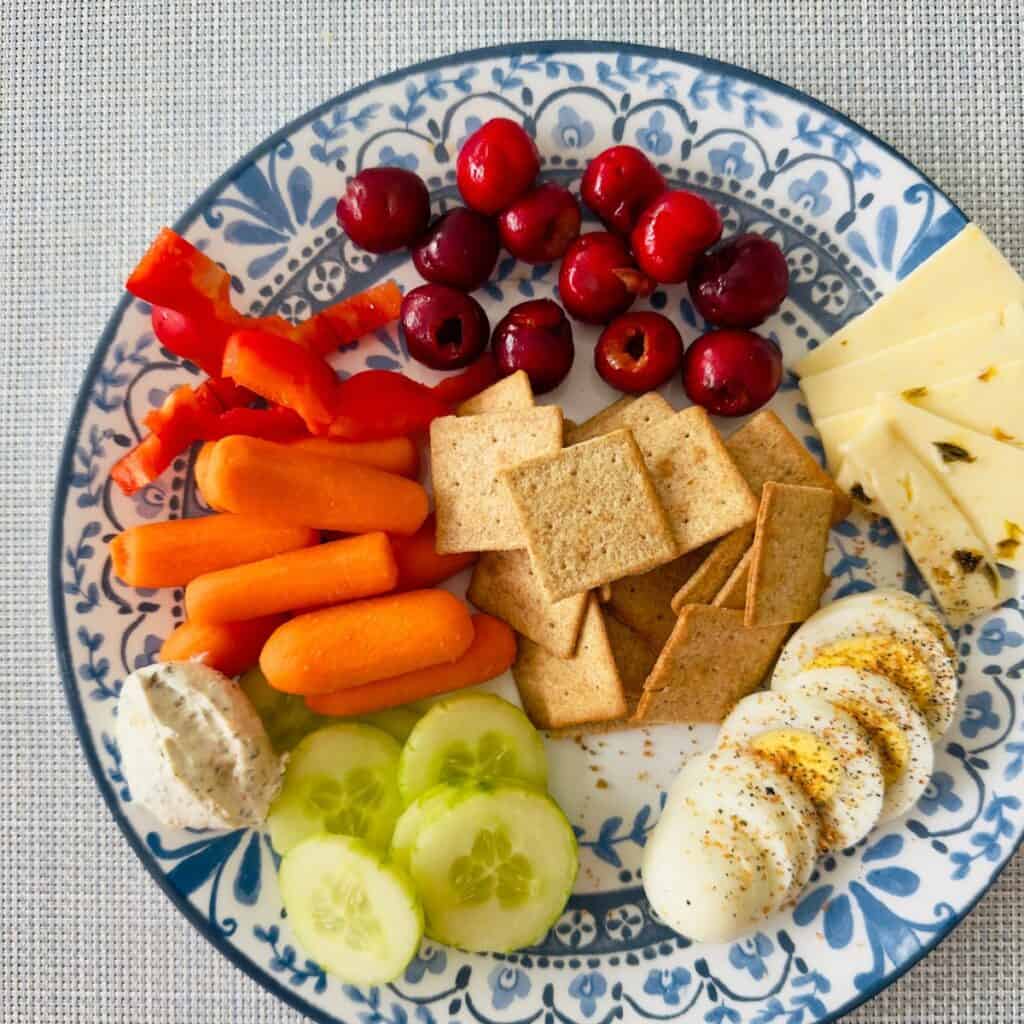 A plate filled with fresh fruit and veggies and a hard boiled egg.