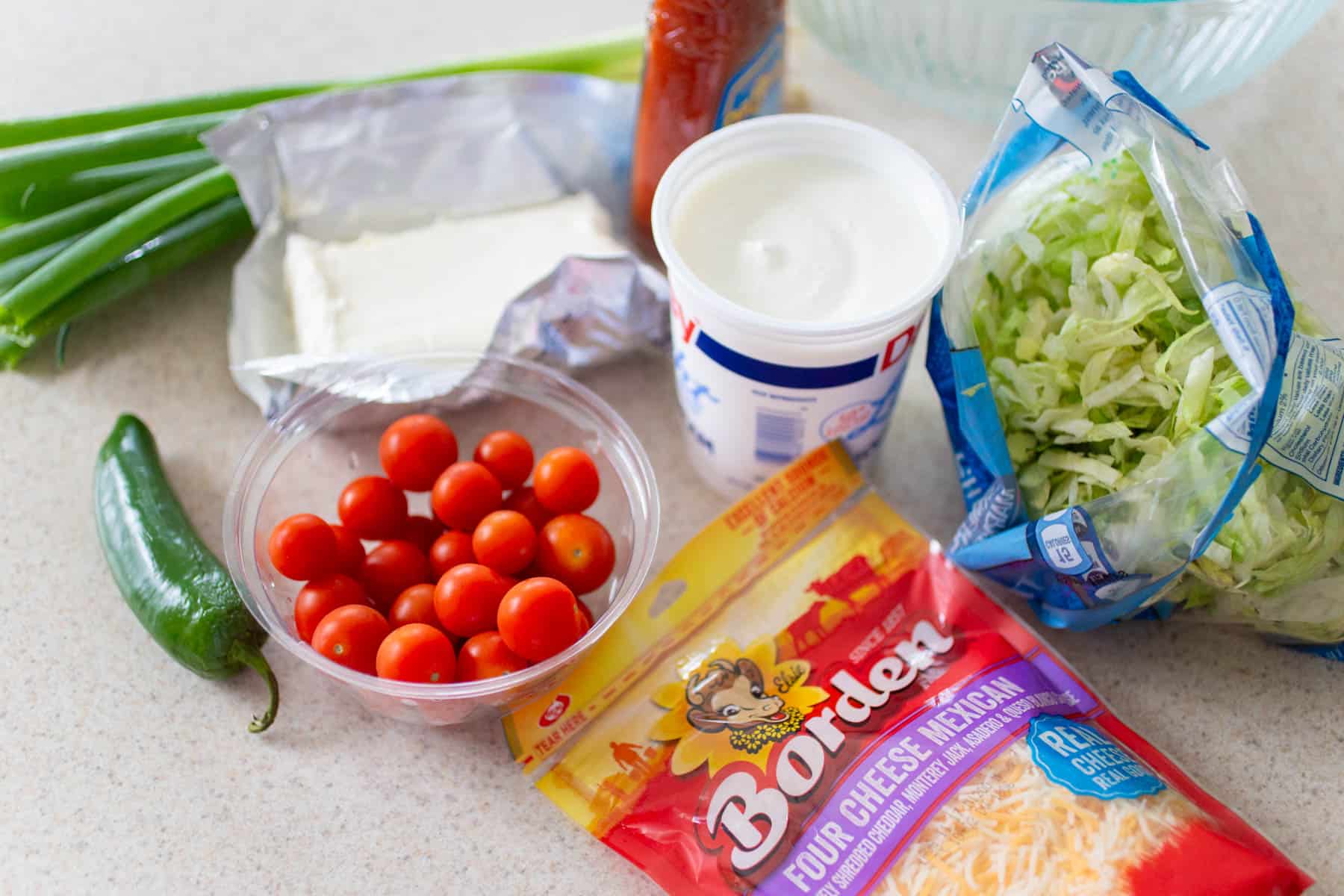 The ingredients to make the taco dip are on the counter.