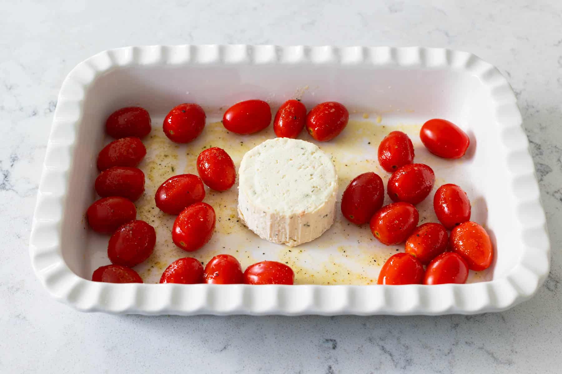 The baking dish is filled with a wheel of boursin cheese surrounded by cherry tomatoes.