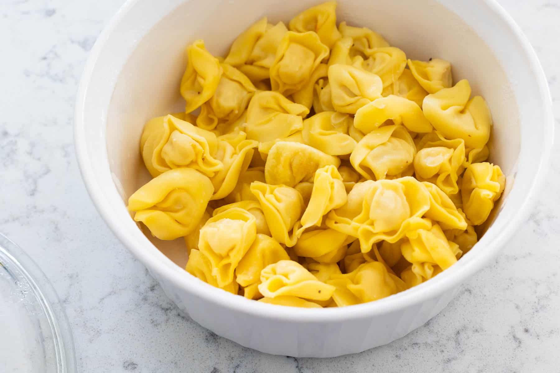 A white dish filled with cheese tortellini.