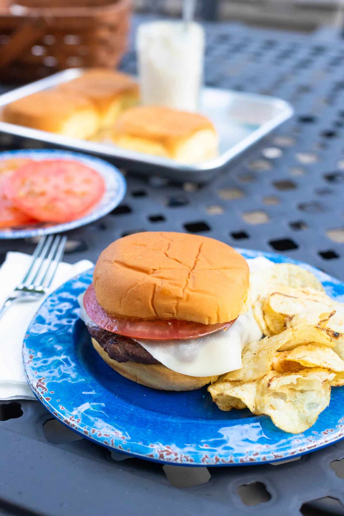 A grilled hamburger on a plate with potato chips.