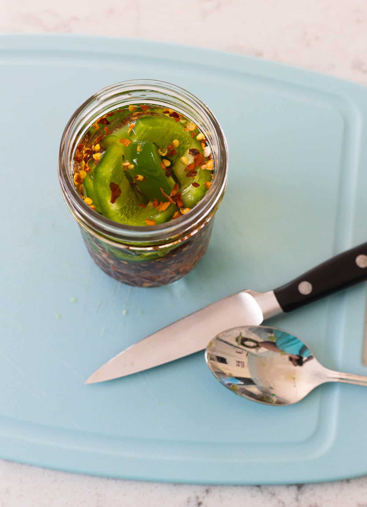 The vinegar jar is on a cutting board with the crushed red pepper flakes floating on top.