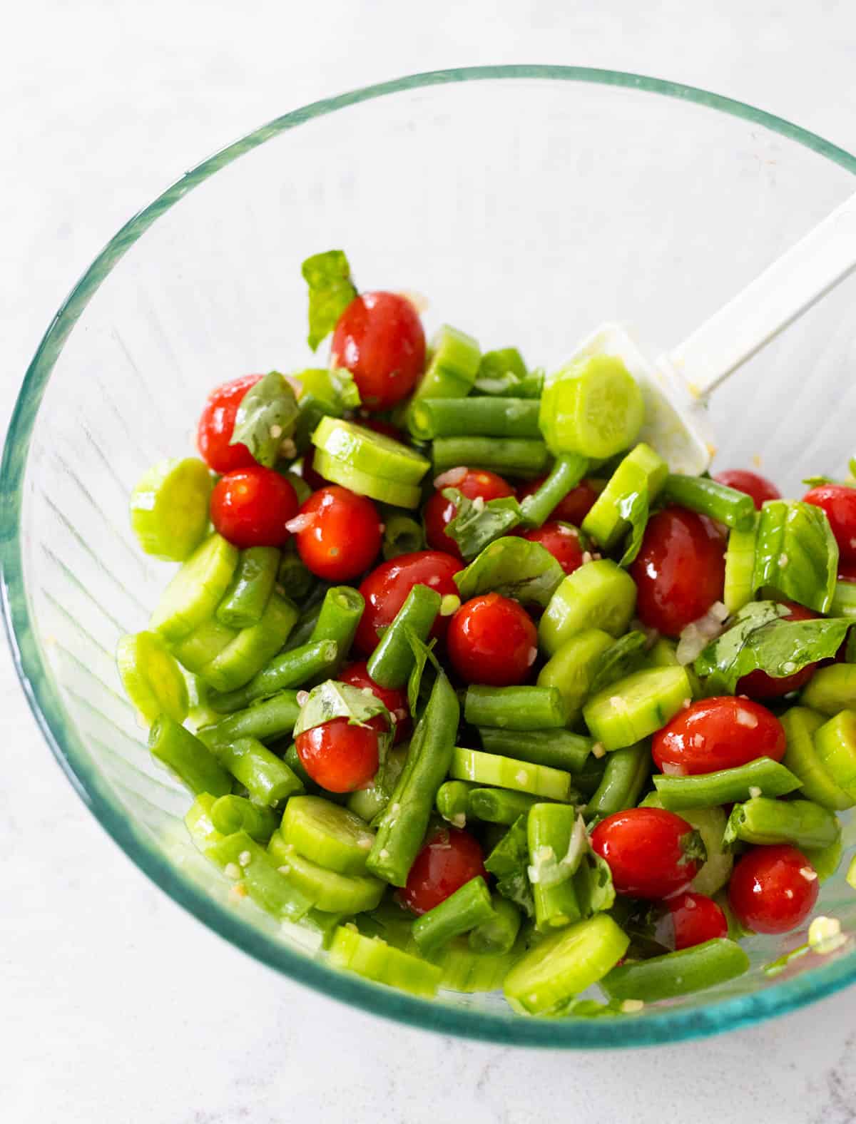 The garlic and olive oil have been stirred into the vegetables in a mixing bowl.
