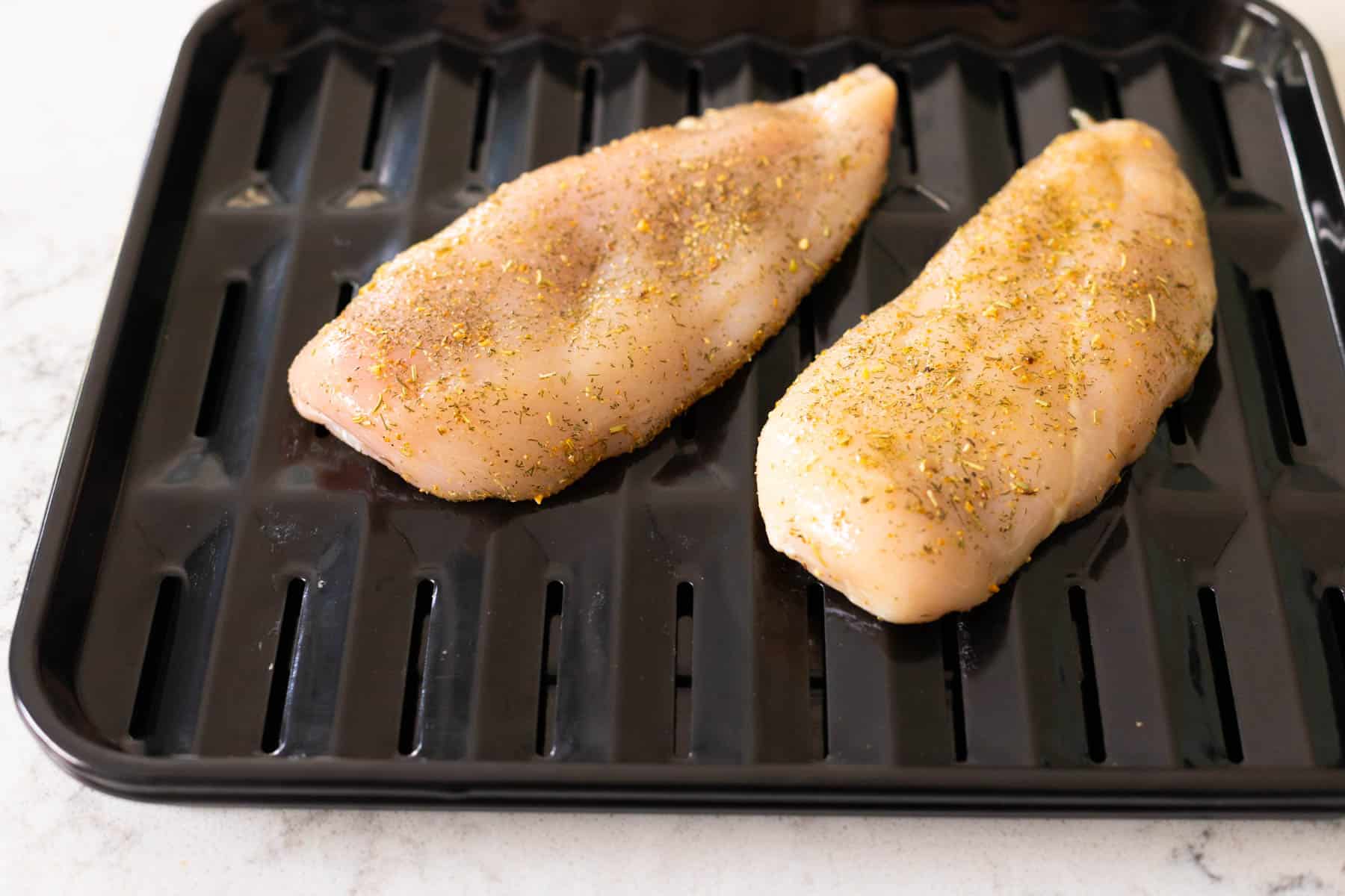 The chicken breasts are on a vented air fryer baking pan.