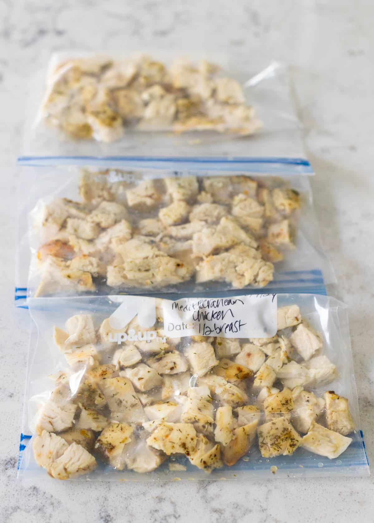 Several small bags of chopped chicken breast are ready to go in the freezer.