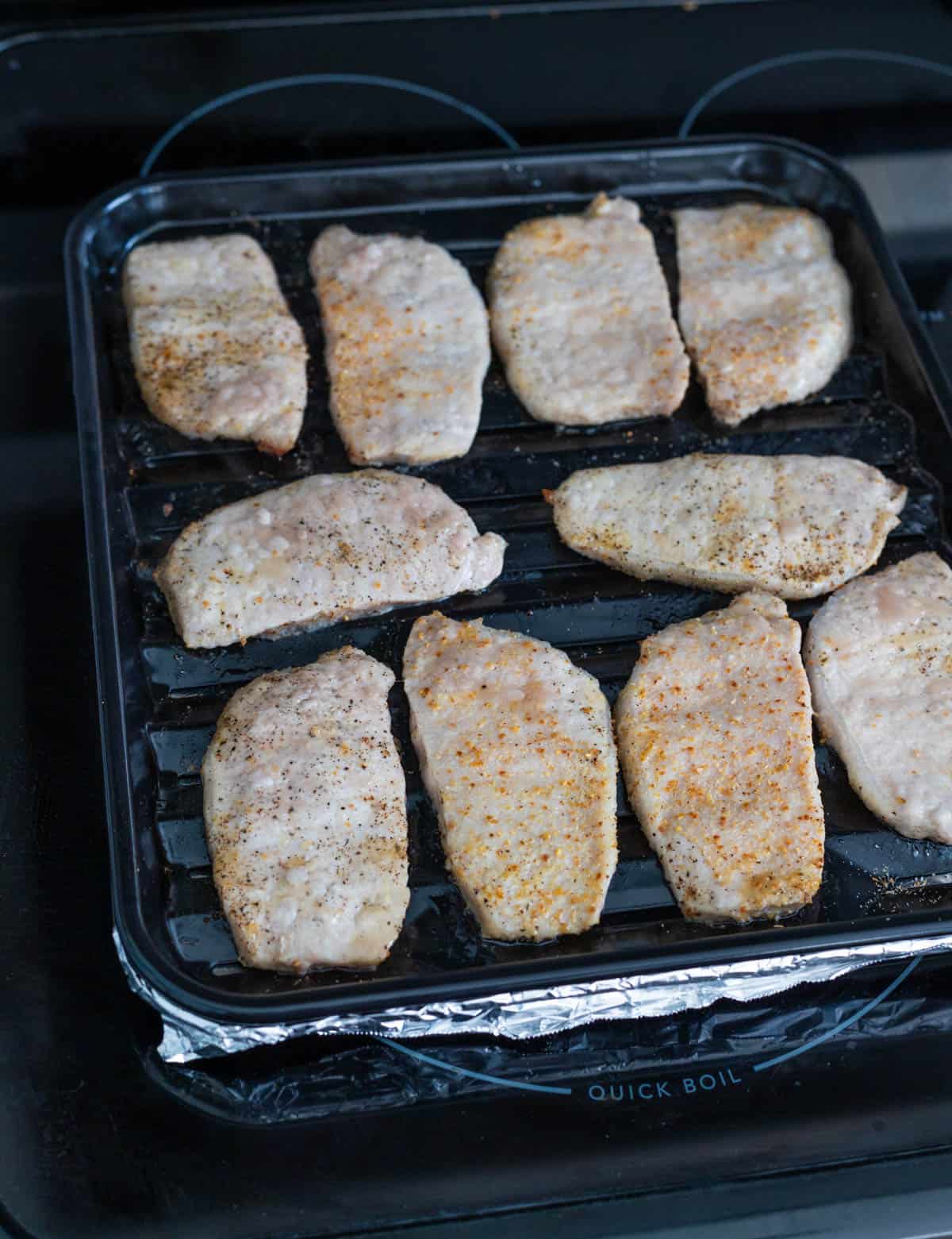The pork chops have finished cooking in the air fryer and are now golden brown.