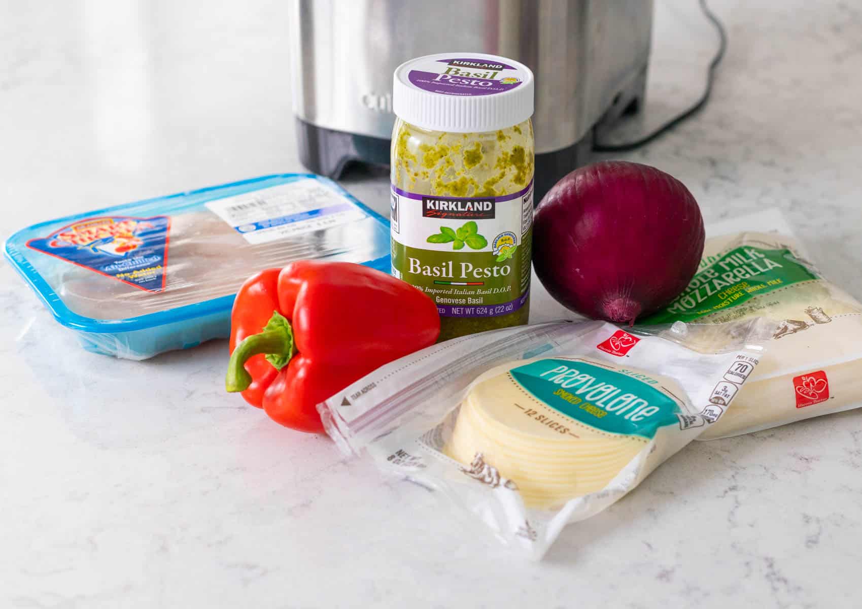 The ingredients to make an easy chicken pesto pizza are on the counter.