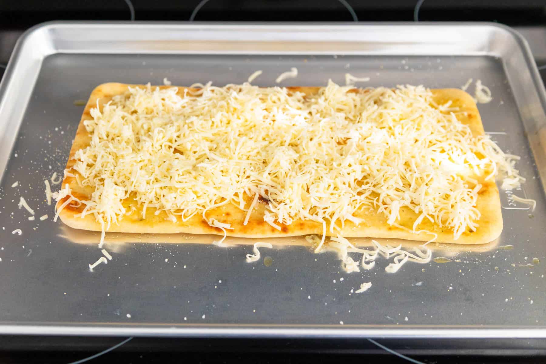 The cheese has been sprinkled over the flatbread.