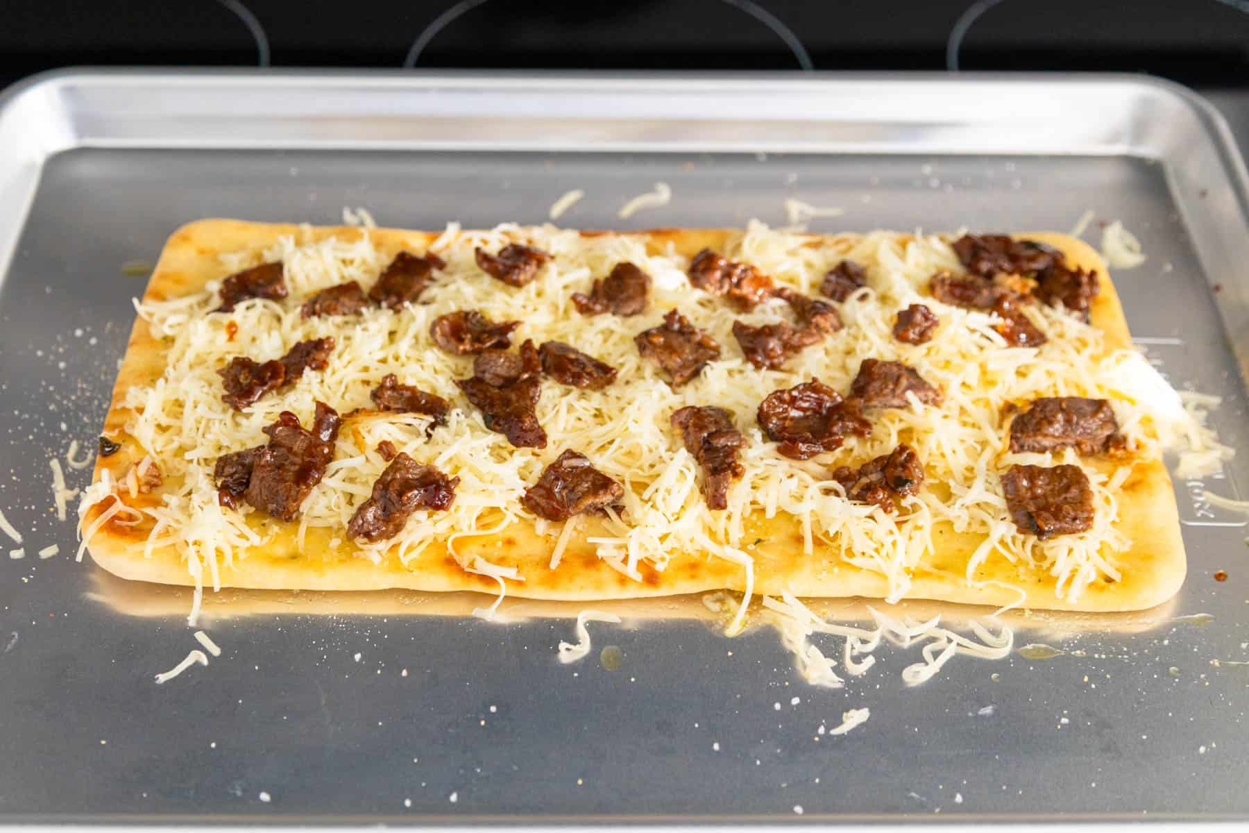 The beef has been chopped up and scattered over the flatbread