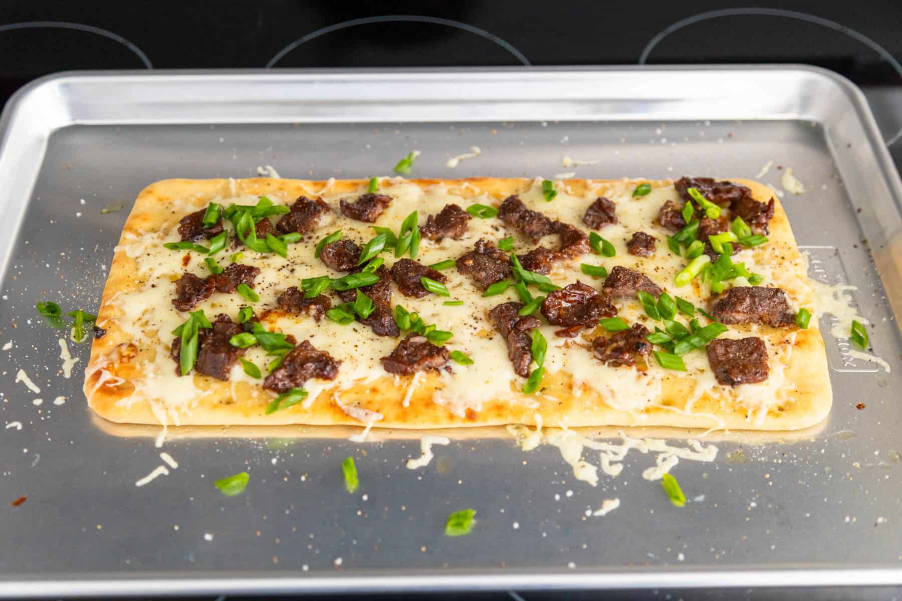 The Mongolian beef flatbread is fresh from the oven and the green onions have been sprinkled over the top.