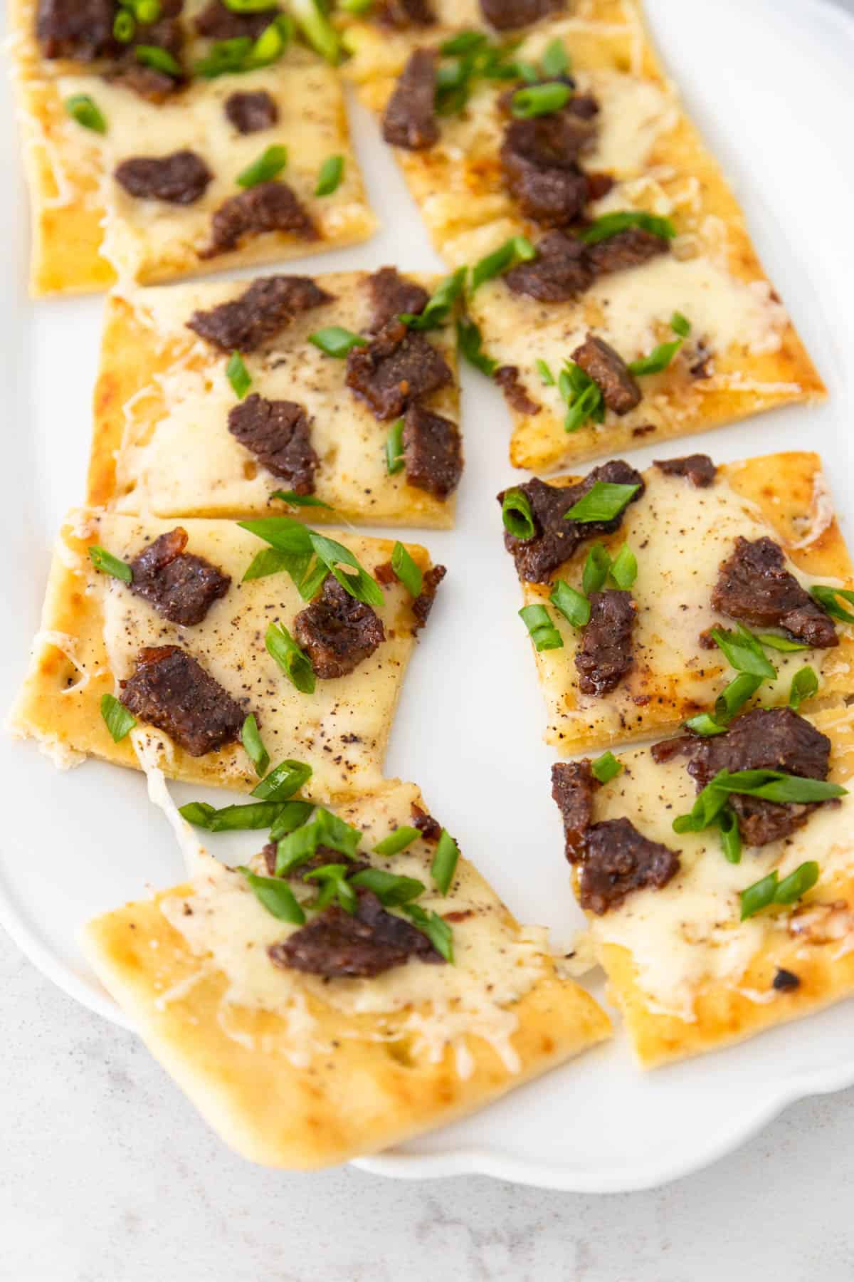The flatbread has been sliced into squares for serving.