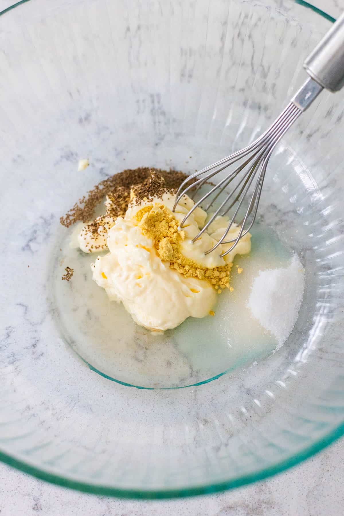The ingredients to make the dressing are in the mixing bowl with a whisk.