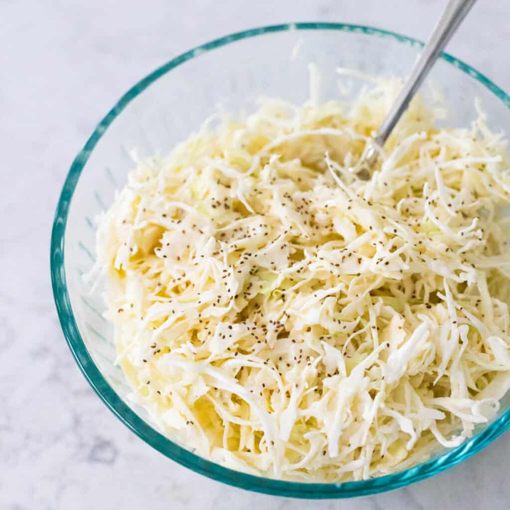 Creamy coleslaw made with angel hair sliced cabbage is in a mixing bowl.