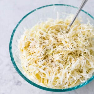 Creamy coleslaw made with angel hair sliced cabbage is in a mixing bowl.