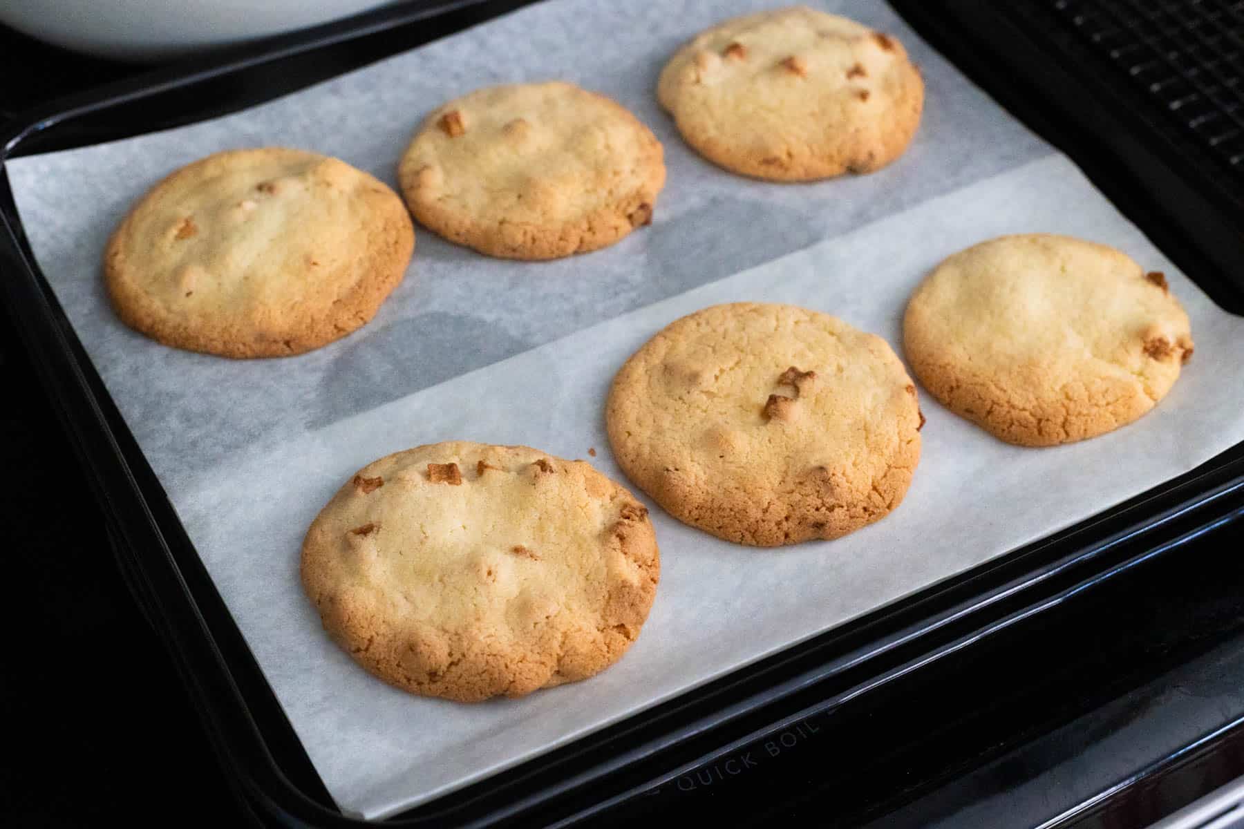 The cookies are on the baking pan lined with parchment paper.