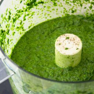 The finished sauce is in the bowl of a food processor.