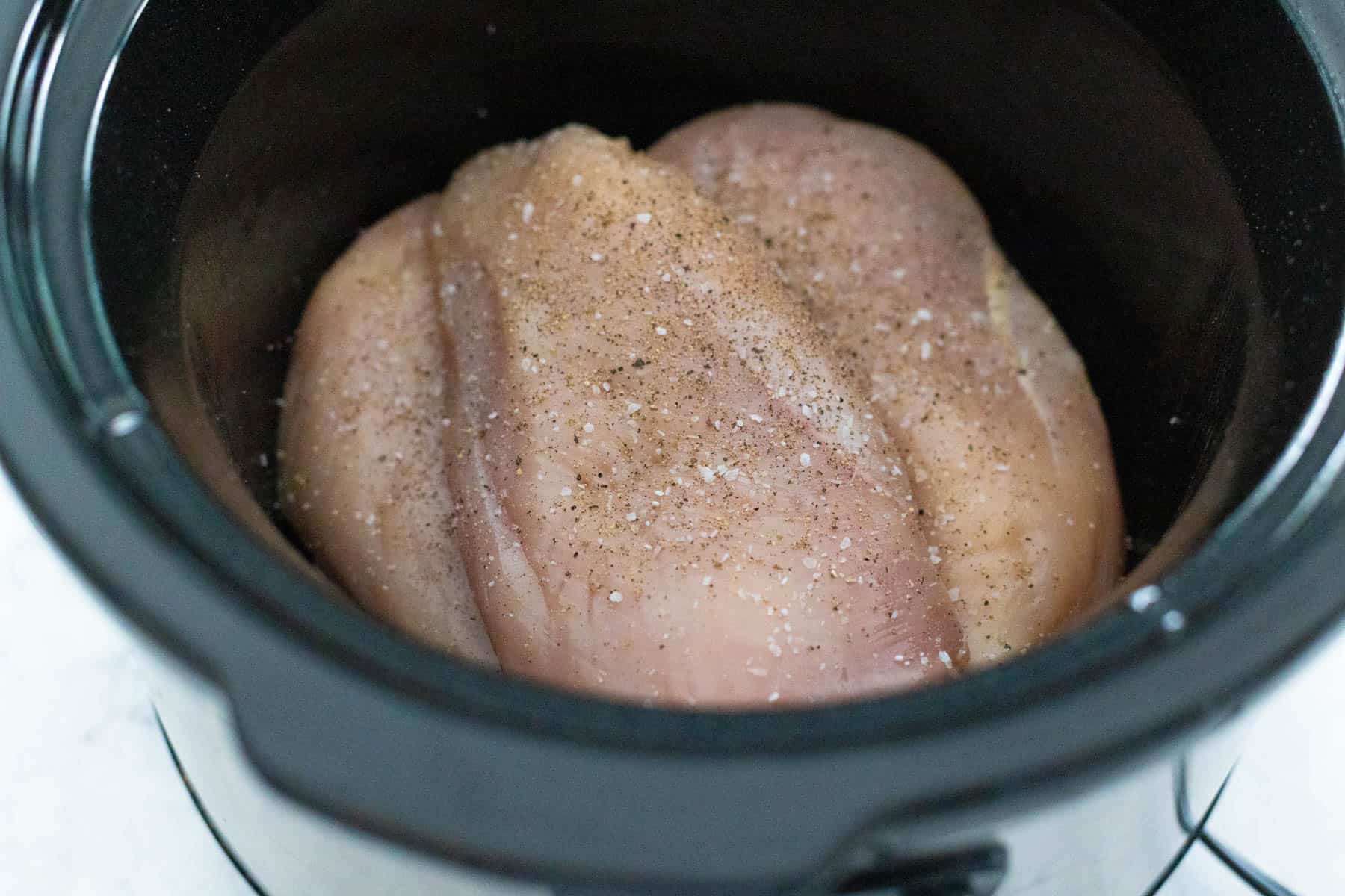 The chicken breasts have been added to the slowcooker and seasoned.