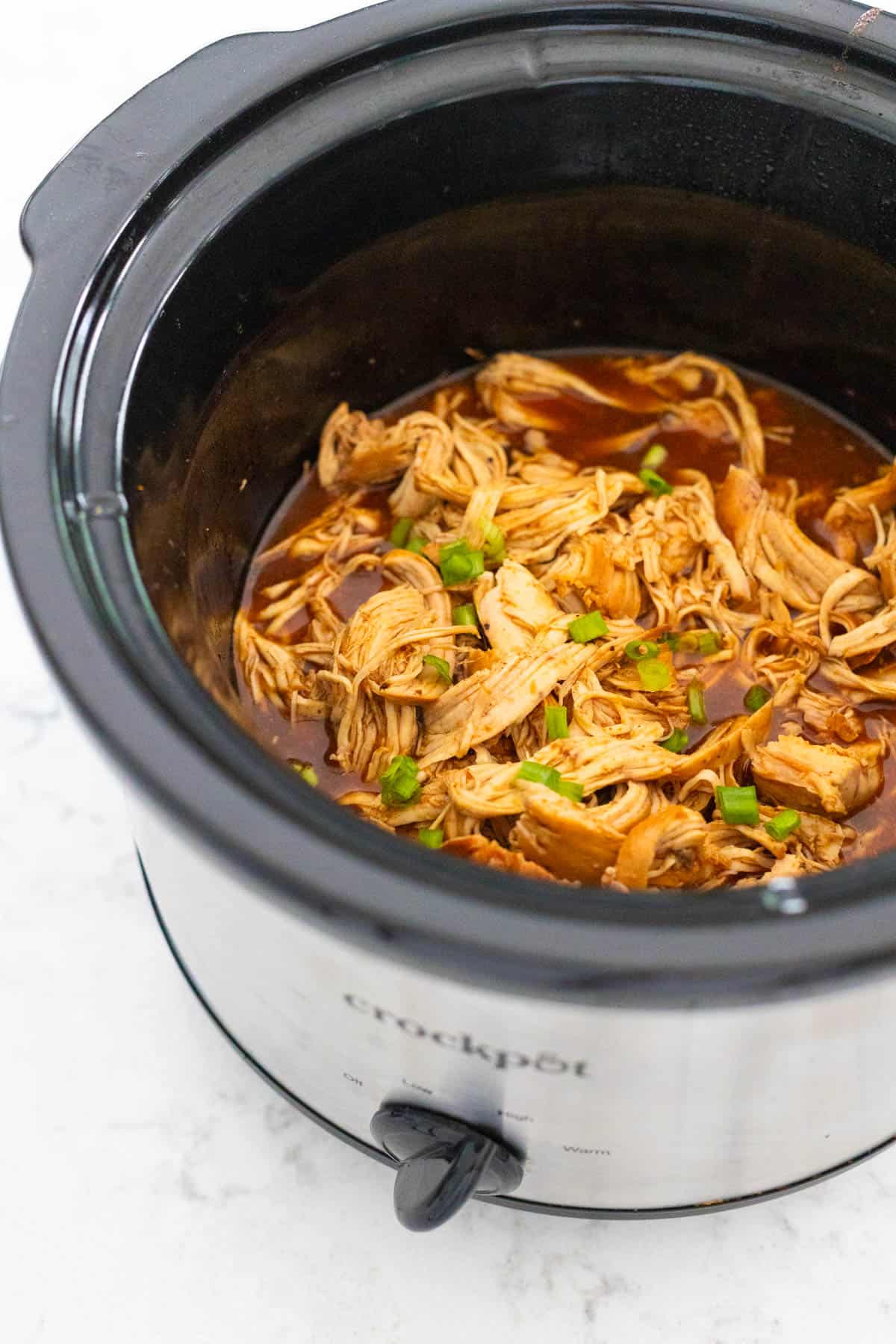 The chicken has been cooked and shredded in the sauce right inside the slowcooker.