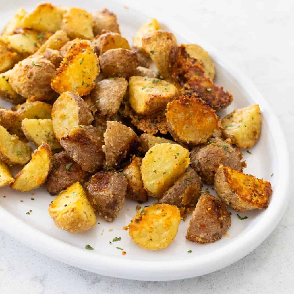 The golden brown roasted potatoes are on a serving platter.