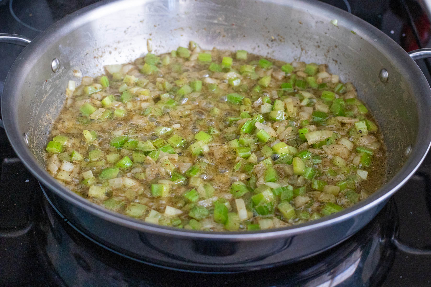 The celery and onions have cooked in butter until softened. The seasonings have been added to the skillet and stirred in.