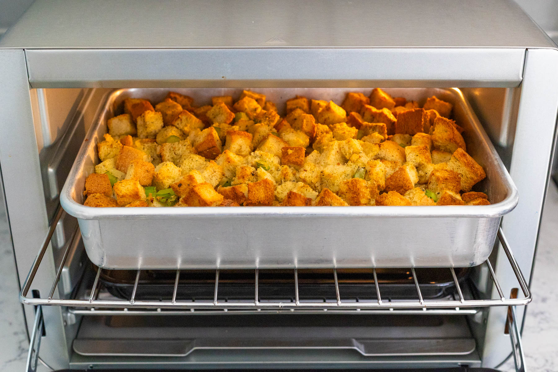 The pan of stuffing is on the top rack of the air fryer.