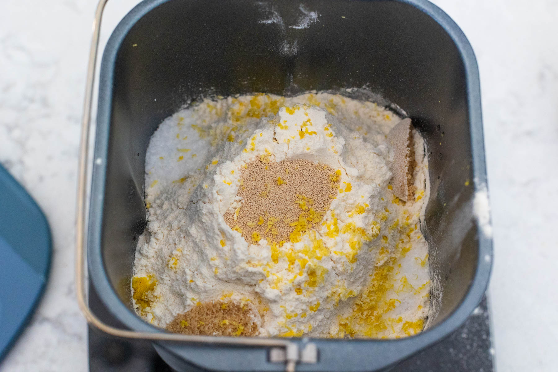 The flour, yeast, and other dry ingredients are now in the bread pan.