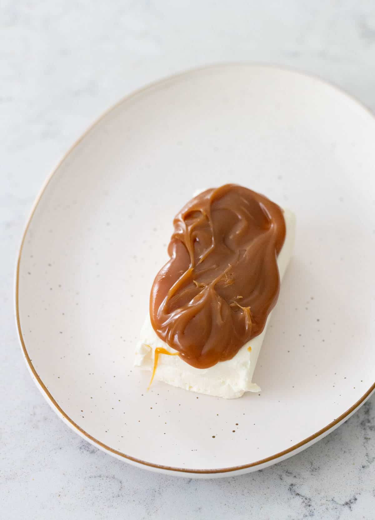 The cream cheese brick has had the caramel sauce spread over the top.