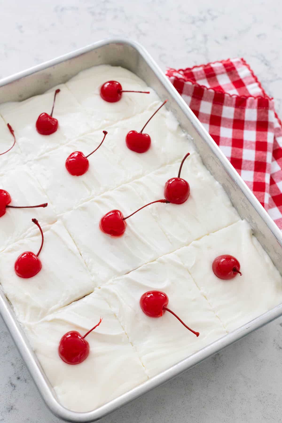 The maraschino cherries with stems have been placed on top of the cake to mark the 12 serving slices you could cut.