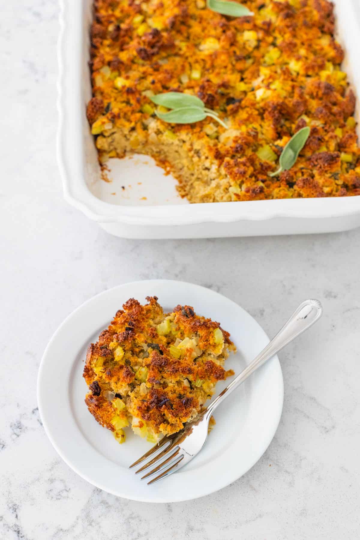 A scoop of the cornbread dressing has been put on a white plate with a fork.