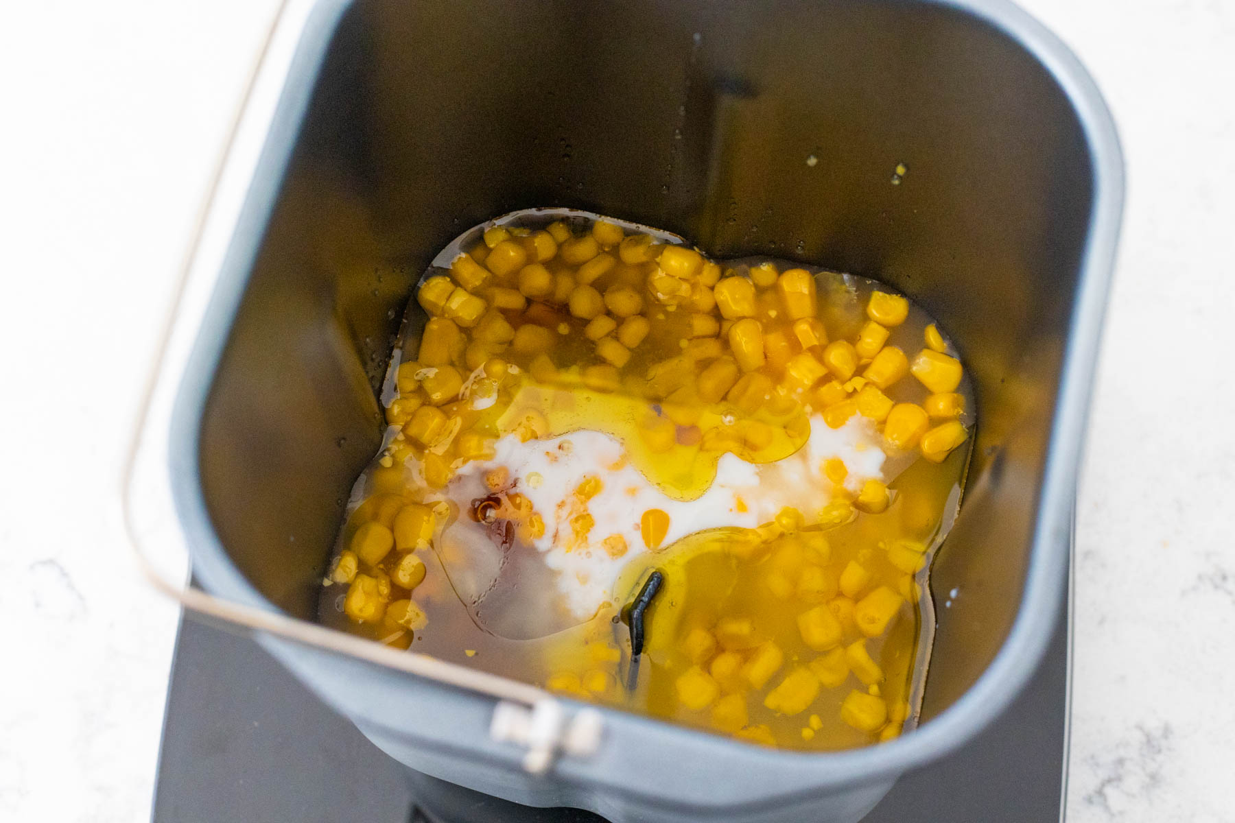 The corn and buttermilk are in the bread machine pan.