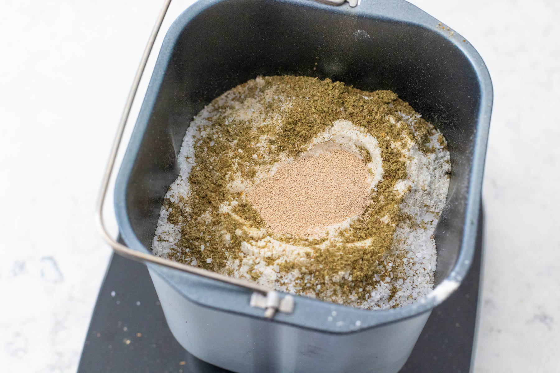 The dry ingredients have been added to the bread pan, the yeast is in a small well in the center.