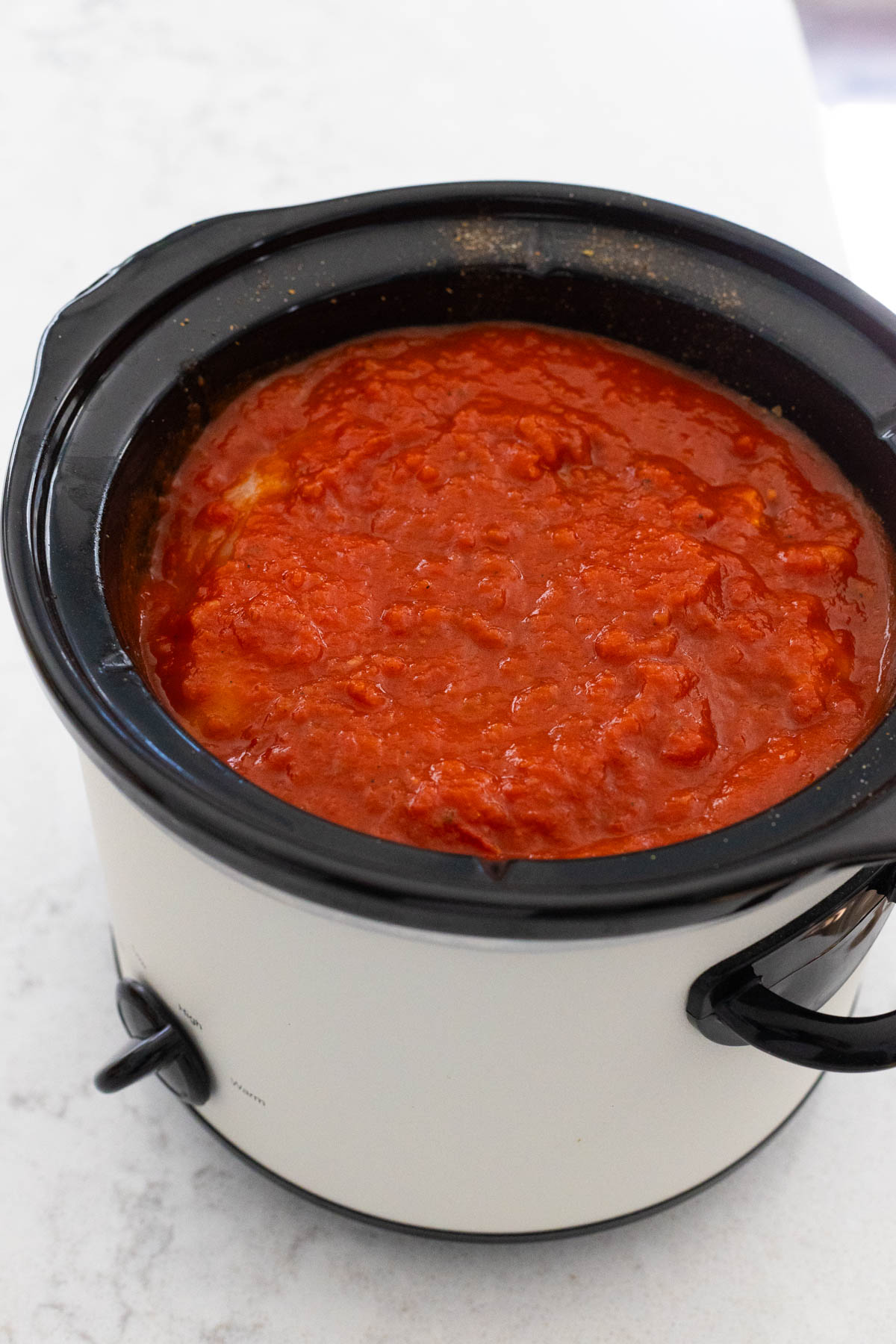 The jar of spaghetti sauce has been poured over the chicken.