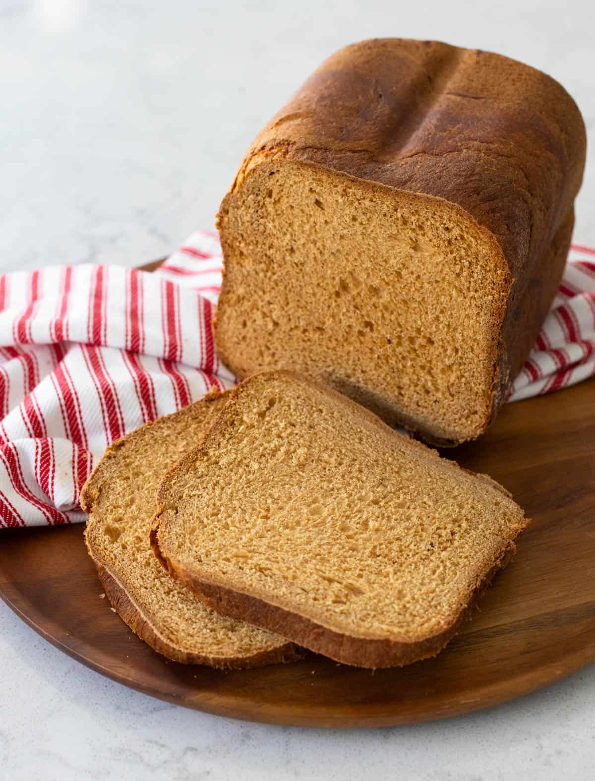 A sliced loaf of gingerbread bread on a wooden plate, showing its soft, spiced interior.