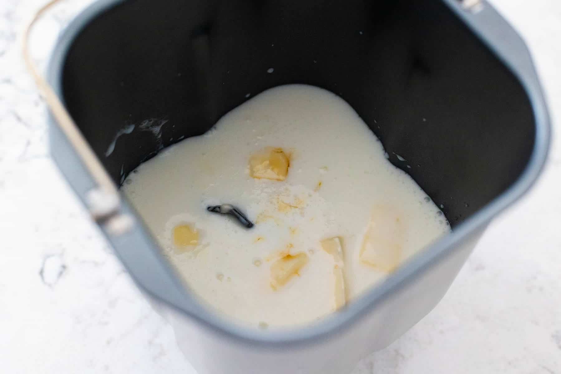 The milk, maple syrup, and the diced butter are in the bread machine pan.