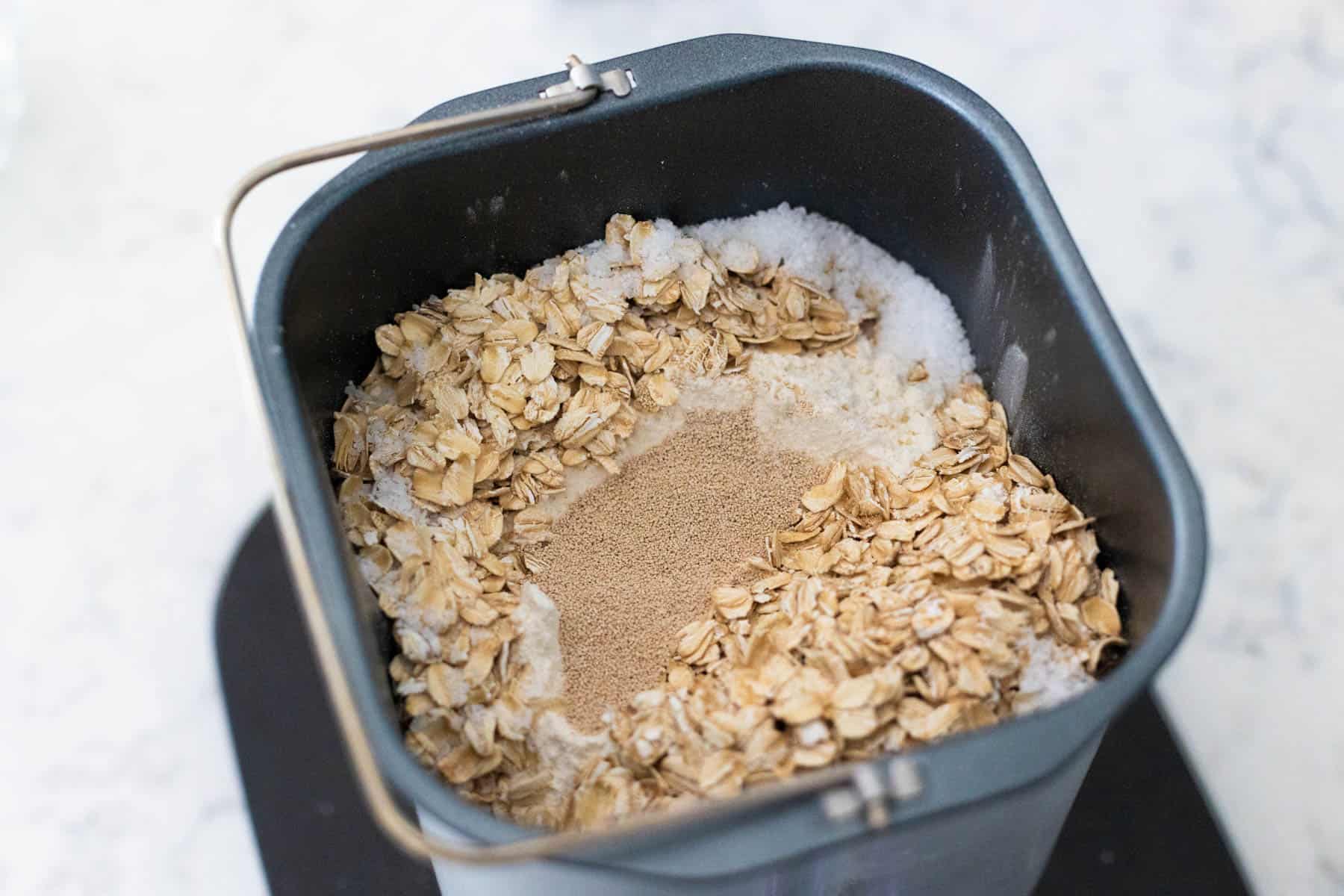 The dry ingredients have been added on top of the wet ingredients in the bread maker pan.