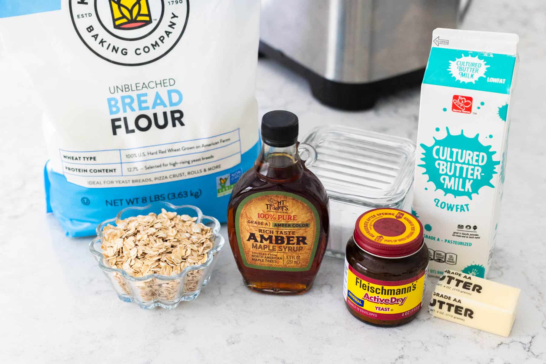 The ingredients to make maple oatmeal bread in the bread machine are on the counter.