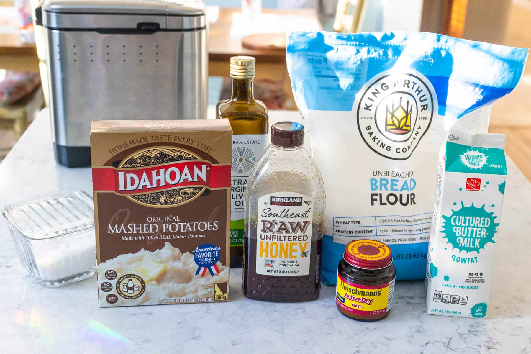The ingredients to make potato bread in the bread maker are on the kitchen counter.