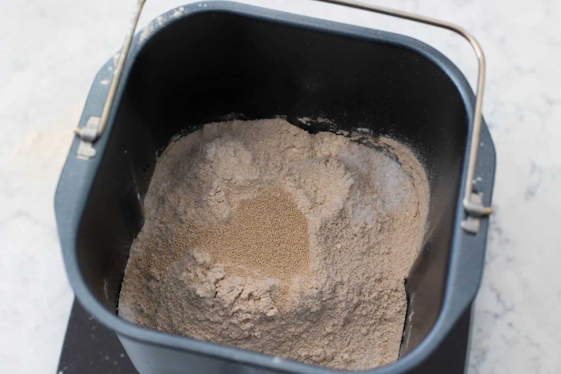 The whole wheat flour and yeast are in the bread pan.