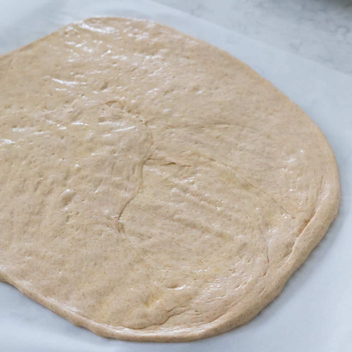 The pizza crust has been patted out into a 12-inch circle.