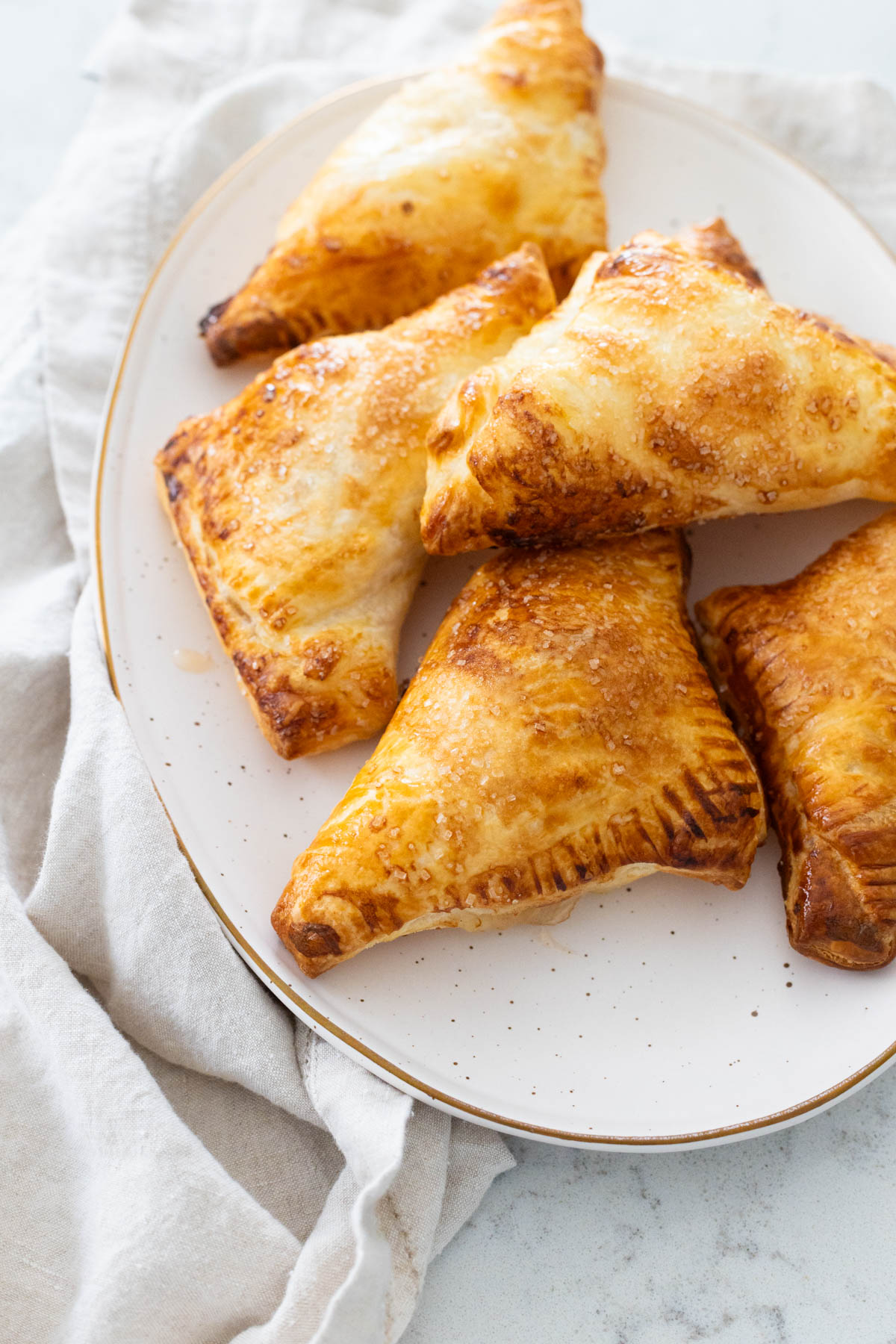The platter of golden brown apple turnovers is ready to be served.