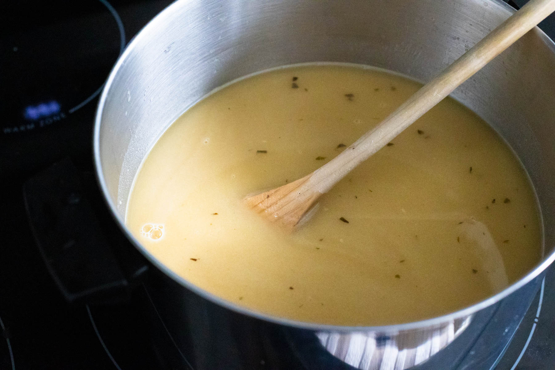 The chicken stock has been added to the gravy and the mixture brought to a simmer in the pot.